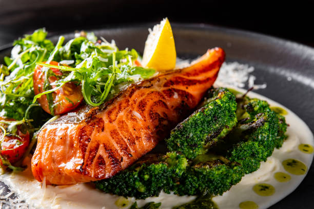fried salmon with creamy sauce, broccoli and salad - pembe somon stok fotoğraflar ve resimler
