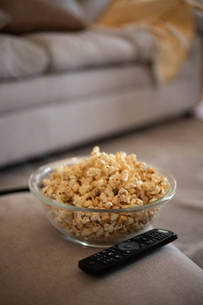 Popcorn with TV remote Popcorn with TV remote remote control on table stock pictures, royalty-free photos & images