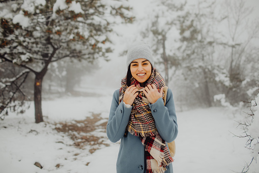 Portrait of a young woman enjoying the snow outside and looking at the camera.