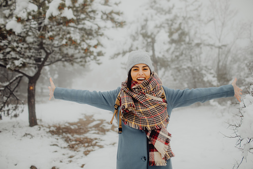 Portrait of a young woman enjoying the snow outside and looking at the camera.