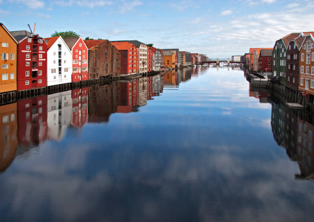panoramic view of old colorful wooden houses with reflections in river Nidelva in the Brygge district in Trondheim, Norway stock photo
