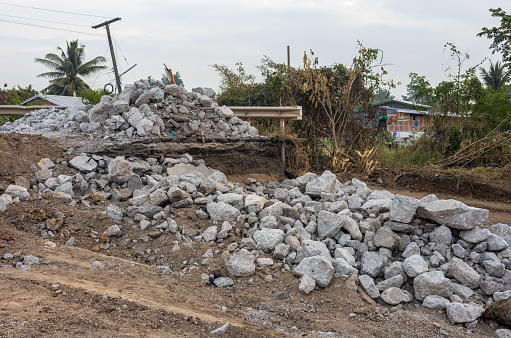 Granite fragments, large and small, were piled up on the ground in arid canals near asphalt roads where they were dug to improve the construction of new bridges in rural Thailand.