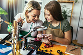 Mother and daughter accessories designers making handmade jewelry in studio workshop. Fashion, creativity and handmade concept.