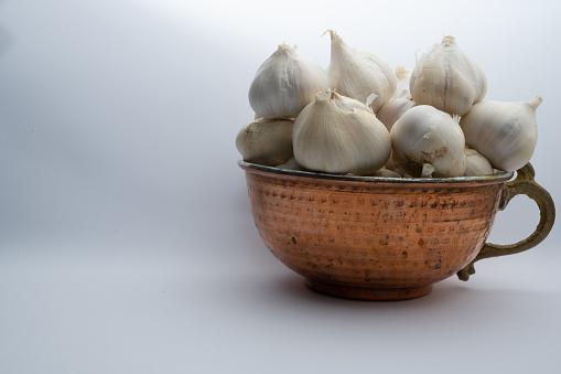 Garlic in copper bowl white background.