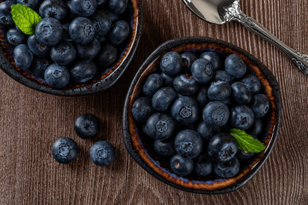 Ripe blueberries in a bowl over wooden background. Ready to eat healthy fruit dessert of wild berries. Tasty fresh blueberry as natural antioxidant. Vegan and vegetarian concept. stock photo