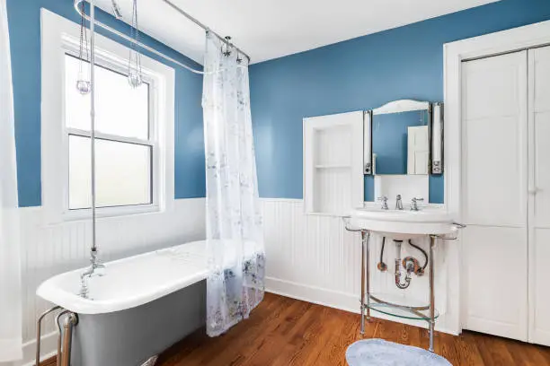 A beautiful blue and white bathroom with a standalone bathtub and white pedestal sink.