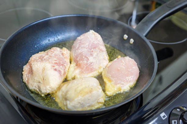Chicken breast fillets frying in a pan.