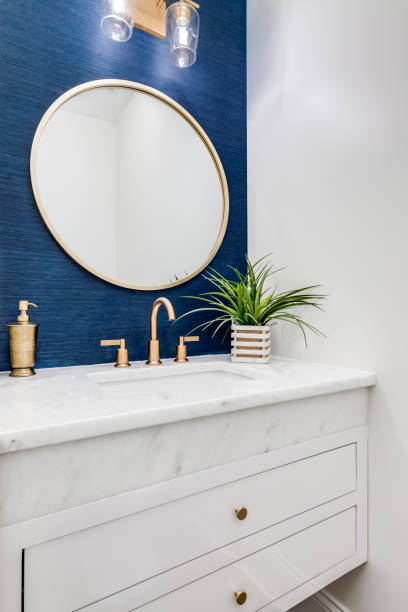 istock A bathroom with blue wallpaper and gold sink and mirror. 1456386518