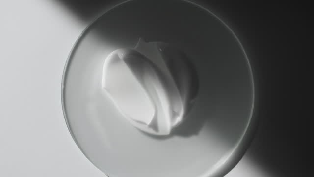 Cream smears on glass appear from shadow on white background