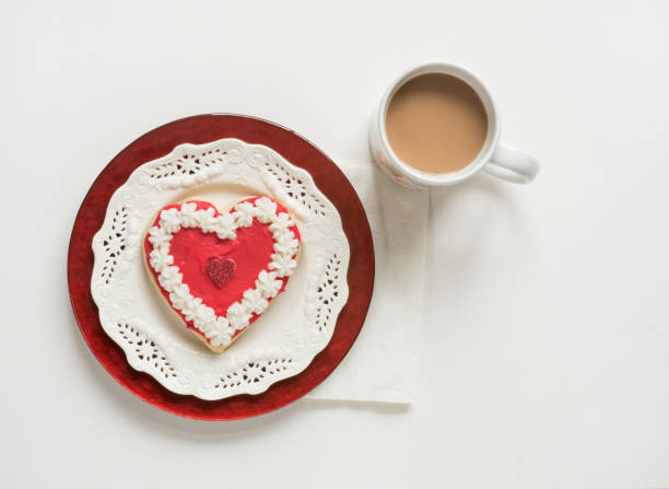 Decorated valentine heart cookie on white and red plates with cup of coffee isolated on white background.