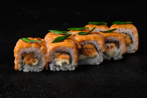 istock Baked salmon sushi roll on black background 1456390803