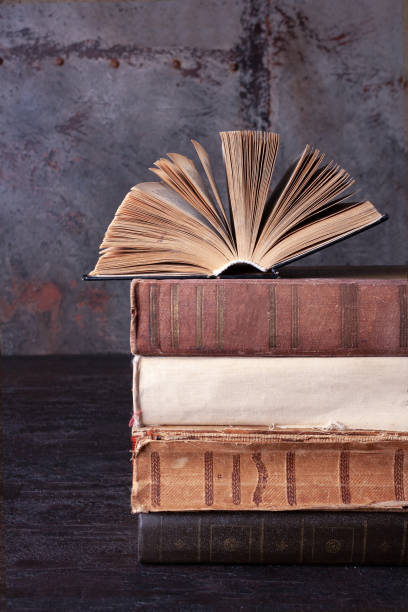 istock an open novel lies on a stack of old books on a brown background 1456390998