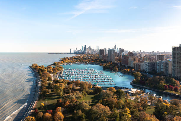 belle photographie aérienne de l’horizon de chicago surplombant le port de belmont et le bord du lac ci-dessous par une journée d’automne ensoleillée avec un feuillage coloré d’automne ci-dessous. - chicago skyline lake nautical vessel photos et images de collection