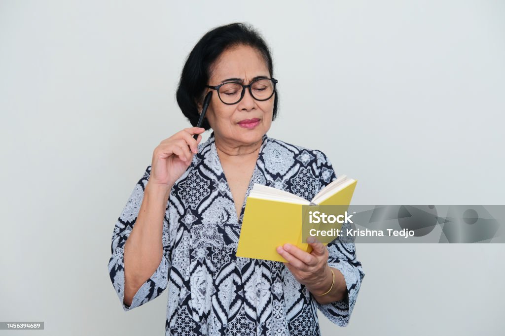 Elderly Asian woman thinking something when reading a book Senior Women Stock Photo