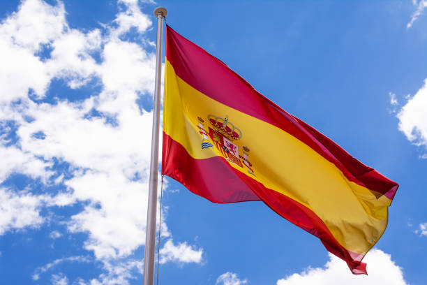 istock Spanish flag in the wind and with blue sky and clouds background 1456395038