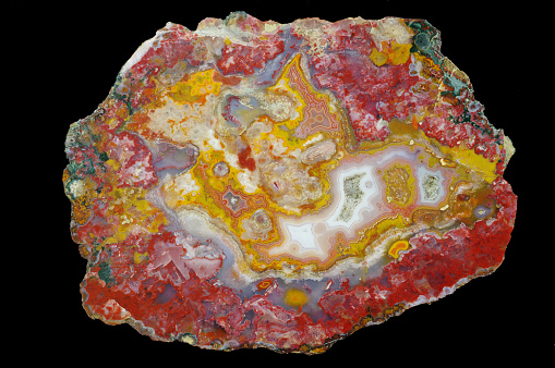 Agate stone with quartz geode. Multicolored silica bands colored with metal oxides are visible. Macro photography of the surface of the cut. Origin: Atlas mountains, Morocco.