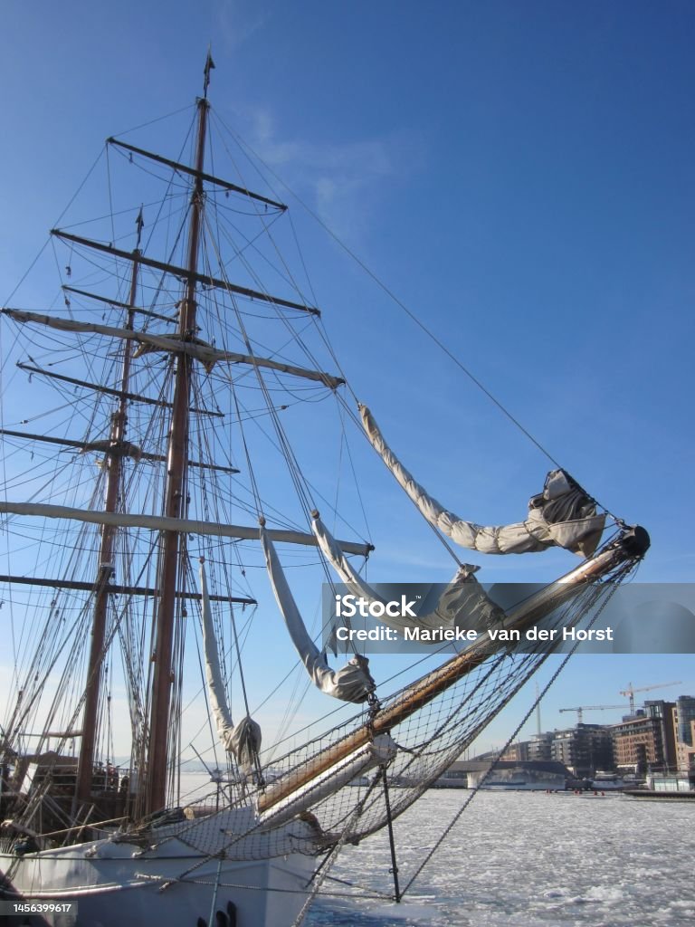 Aker Brygge in Oslo with a sailing ship lying in the Oslofjord  with ice floes, Norway Aker Brygge in Oslo with a sailing ship lying in the Oslofjord  with ice floes, Norway, on a beautiful cold sunny day with blue sky. Architecture Stock Photo