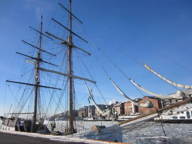 Aker Brygge in Oslo with a sailing ship lying in the Oslofjord  with ice floes, Norway, on a beautiful cold sunny day with blue sky.