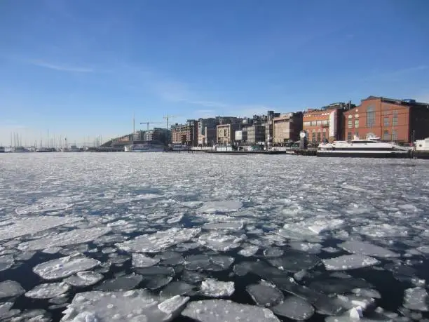 Aker Brygge in Oslo and ice floes in the Oslofjord, Norway, on a beautiful cold sunny day with blue sky.