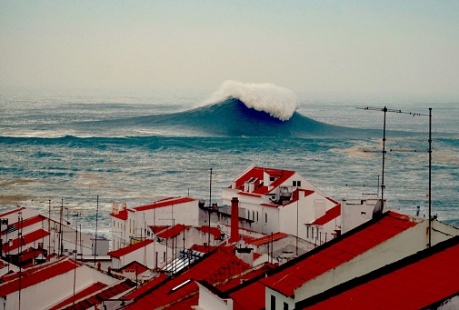 Huge waves break out to sea over the Nazare canyon, viewed here from Nazare Old Town