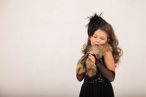 Portrait of fashionable little girl model posing wearing art vintage stylish black dress on white background, pensive. Studio shot retro style child. Fashion style concept. Copy text space for ad