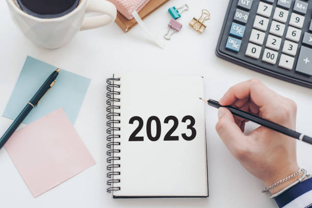 istock female hand writing down to-do list and plans for 2023 to notebook. Goals for next year 1456401330