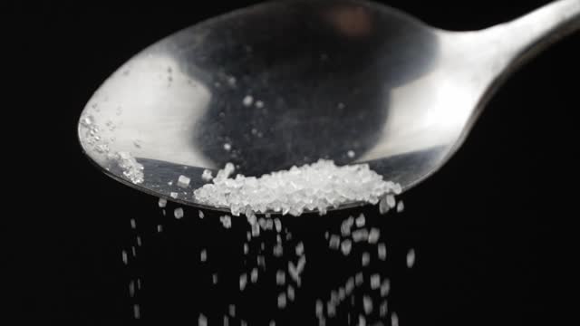 spoon full of powdered sugar crystals in teaspoon side view filled with sugar