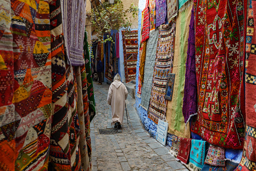 North Africa. Morocco. Chefchaouen. An old man dressed in a bournous walking in a street of the medina
