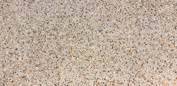 A close-up background texture of the exterior surface of a house finished with a pebbledash exterior of small stones and stone chips.