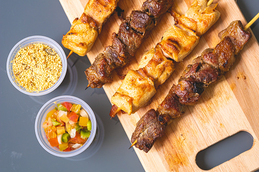 Skewers with meat known in Brazil by the name of churrasquinho. Vinaigrette and farofa in the composition. Brazilian food, barbecue.