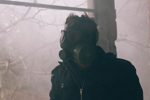 Adult man wear gas mask because air is poisoned with toxic gas
