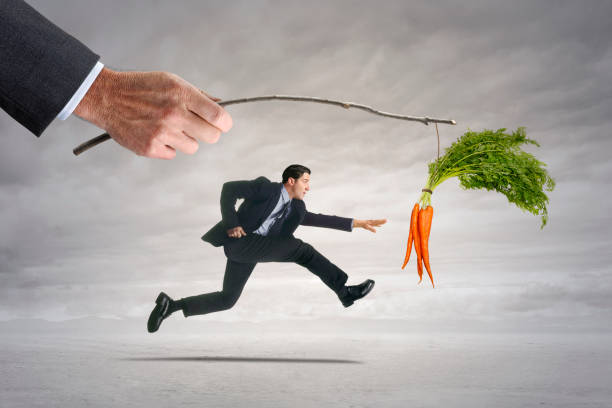 istock Businessman Chasing Carrots Dangling From A Stick 1456419124