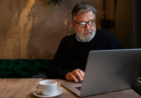 Mature businessman working on laptop at cafe