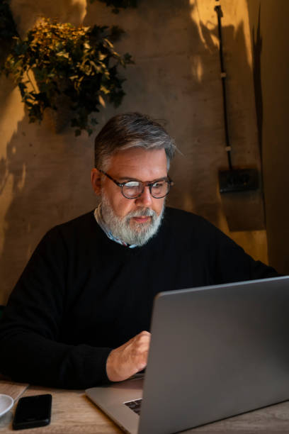 istock Mature businessman working on laptop at cafe 1456422114