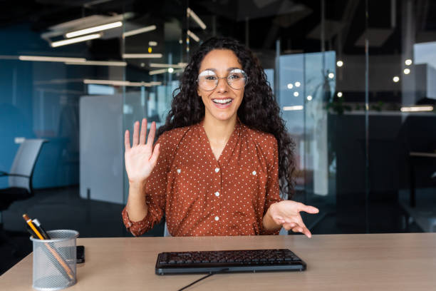 istock Online customer support video call, Latin American woman looking at web camera smiling and consulting customers, helpline worker working inside office 1456423728