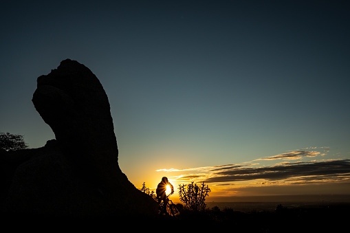a man in silhouette makes his way across the landscape at sunset while riding his mountain biking.  such beautiful nature scenery and adventure and exercise opportunities abound in central new mexico.