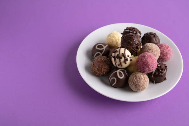photo of candy in a chocolate shell lying next to each other on a plate on a colored background
