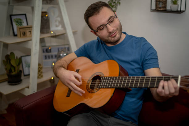 istock Young man playing a guitar at home 1456426641