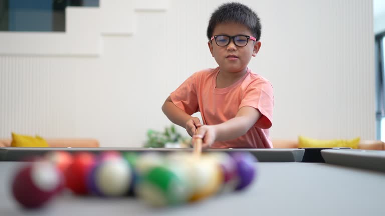 Asian boy  as a beginner practices and plays snooker or pool