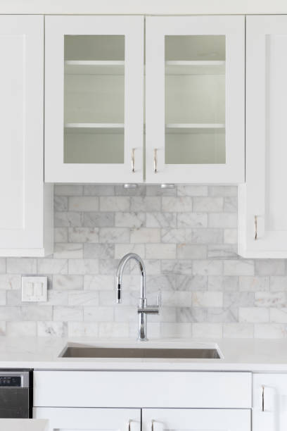 istock A white kitchen detail with a marble backsplash and chrome faucet. 1456429518