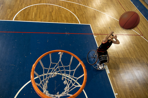 Man in wheelchair practicing basketball