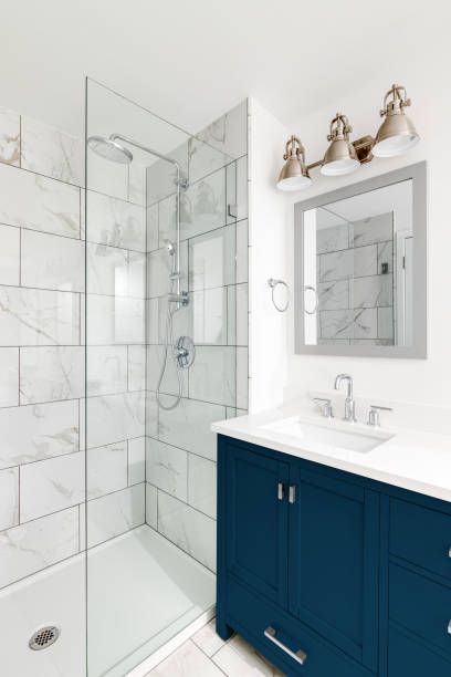 istock A bathroom with a blue cabinet, white countertop, and marble tiled shower. 1456430112