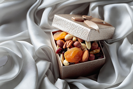 Dried fruits and nuts in a gift box on a grey cloth.