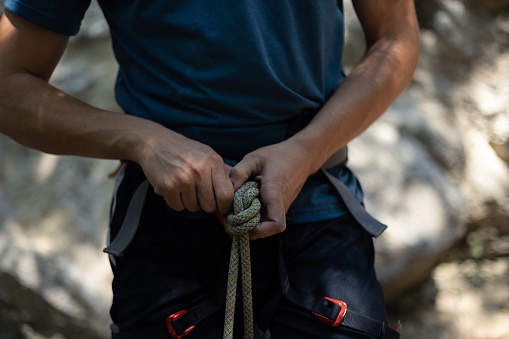 A closeup of the rock climber preparing the rope for climbing.