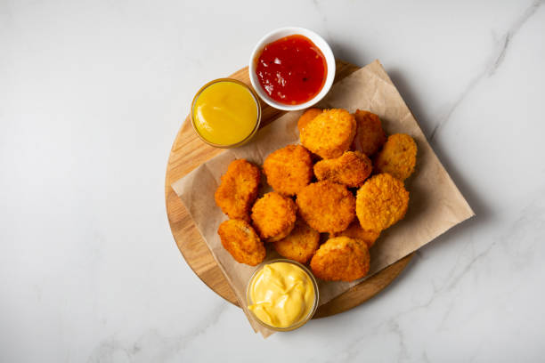 istock Close up of Chicken crunchy nuggest on plate and sauces dips on light surface 1456438108