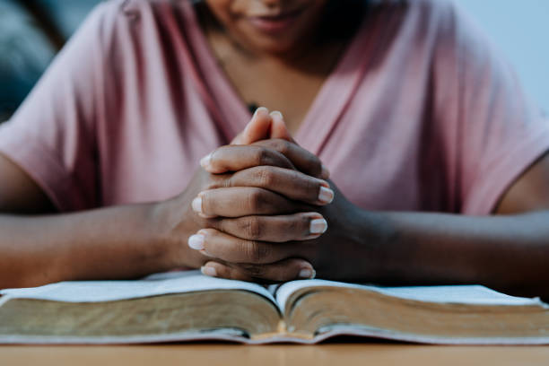 mujer orando con la biblia sobre la mesa - christian mujer leyendo la biblia fotografías e imágenes de stock