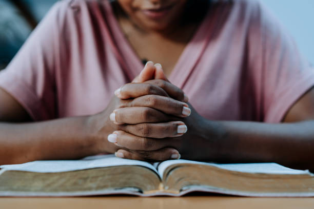 woman praying with the bible on the table - biddende handen stockfoto's en -beelden