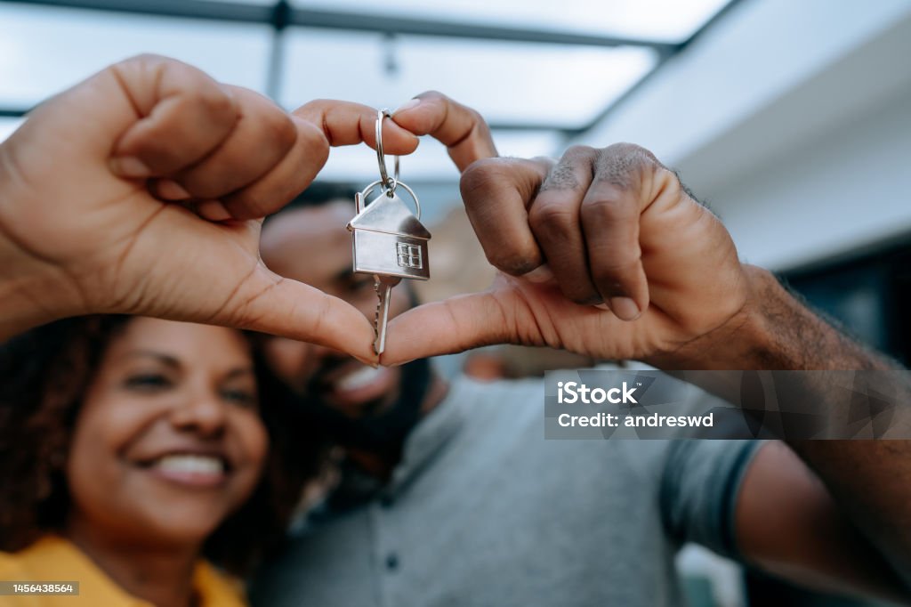 Couple second key to new home with hand in heart symbol House Stock Photo