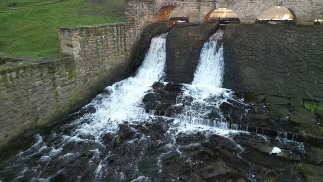 dam of breeding fish pond has a canal safety overflow similar to a weir. water flows under a stone bridge with several arches. bridge on crown of dam with, source drinking drink, dry, drought, tank