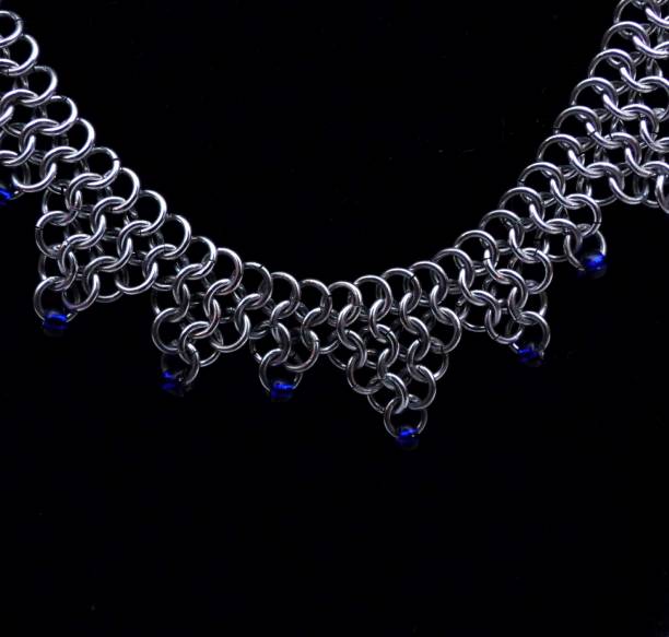 Silver Triangle Drop Chain Mail Necklace Close-up of a silver triangle drop chain mail necklace on a black background. chain mail stock pictures, royalty-free photos & images